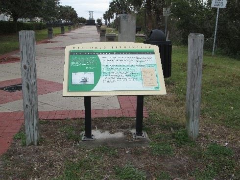 Photo of a green-colored graphic panel sitting in front of a 

sidewalk.