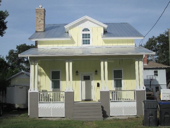 Photo of a yellow house with a white porch.