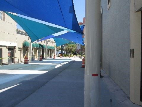 A photo showing new concrete on the ground, close to the pillars that hold up the shade sails in a 

courtyard.