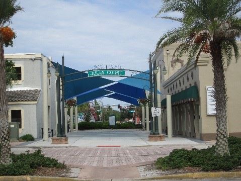 Photo showing a courtyard after renovation, with new concrete, shade sails and an arch sign.